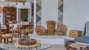 A dining area with wooden furniture, a glass table, and a decorative wall with geometric patterns. - Villa Giari 8 Emma Villas (Ceglie Messapica)
