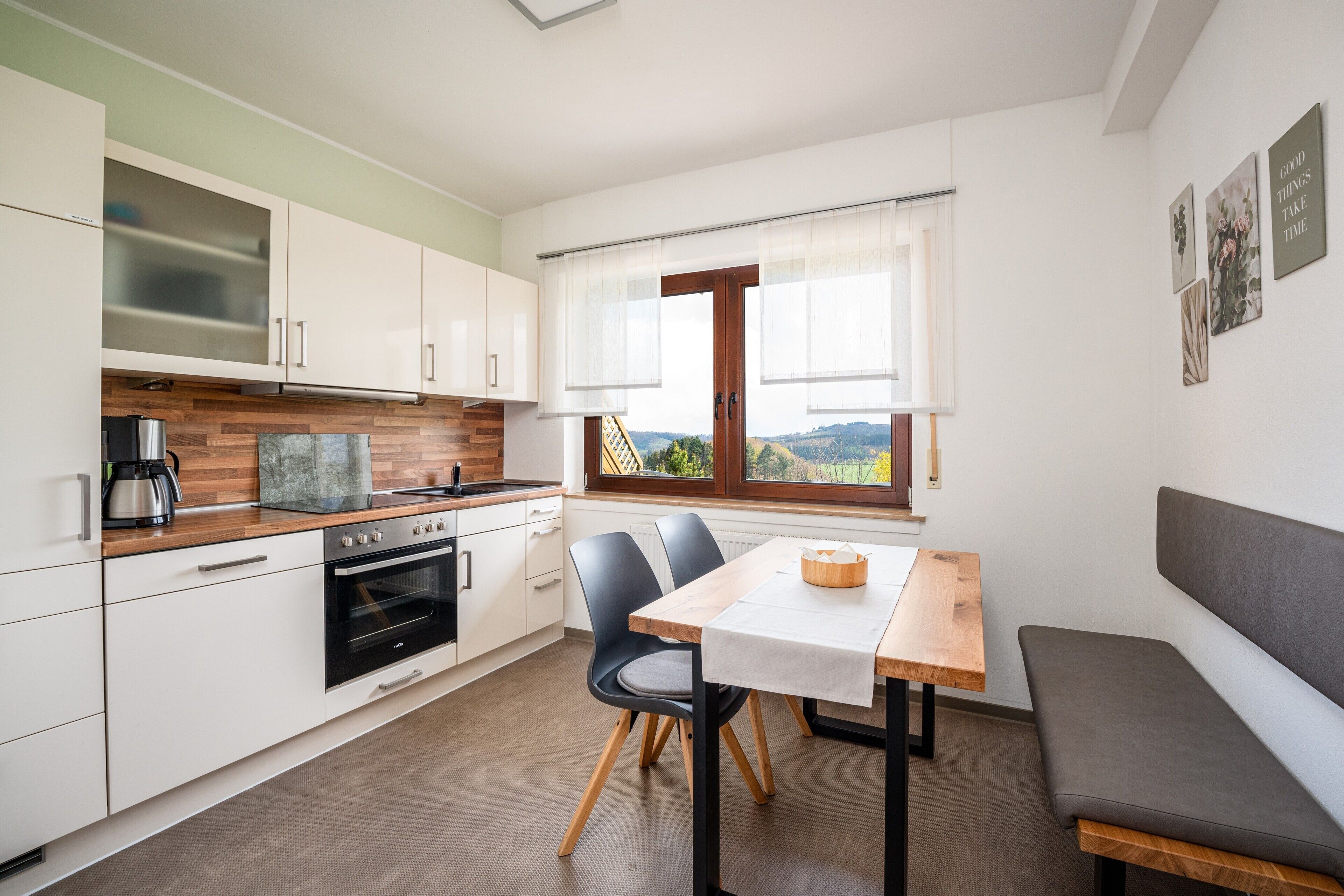 A modern kitchen with white cabinets, a wooden countertop, and a built-in oven.
