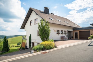 Ein zweistöckiges Haus mit geneigtem Dach, einer Garage und einem angelegten Vorgarten.