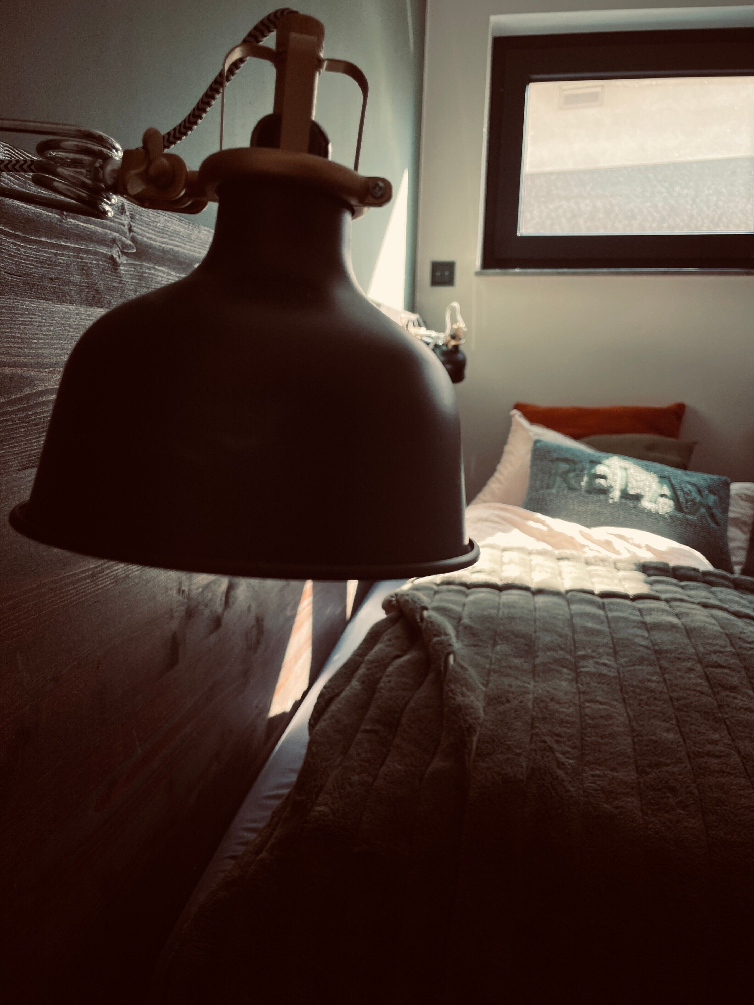 A bed with a quilt, a bedside lamp, and a window with a view.