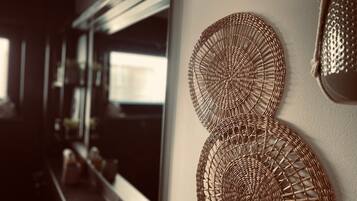 Una habitación con un espejo grande, un adorno tejido en la pared y una ventana con vistas.