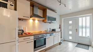 Une cuisine moderne avec des meubles blancs, un plan de travail en bois, des appareils électroménagers en acier inoxydable et une grande fenêtre.