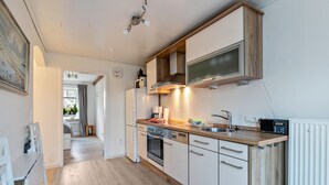 Une cuisine moderne dotée d’un plan de travail en bois, d’appareils électroménagers intégrés et donnant sur la salle à manger.