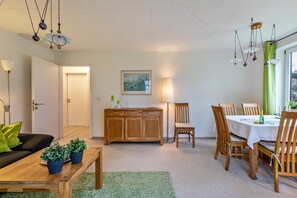 Ein modernes Wohnzimmer mit einem Holzesstisch, Stühlen, einer Couch und einem Schrank.
