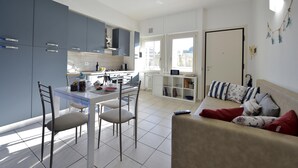 A modern kitchen with a dining area, a sofa, and a view of the city. - Purpo in Cattolica With 1 Bedrooms and 1 Bathrooms (Cattolica)