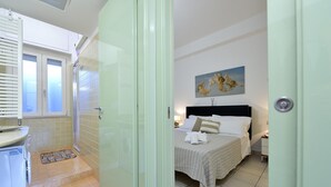 A hotel room with a bed, a nightstand, a painting on the wall, and a bathroom with a shower and toilet. - Purpo in Cattolica With 1 Bedrooms and 1 Bathrooms (Cattolica)