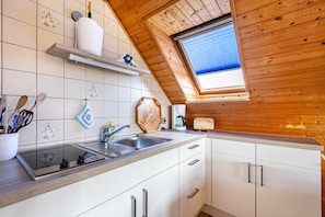Eine Küche mit Holzbalkendecke, einem Fenster, einer Spüle und einer Arbeitsplatte.