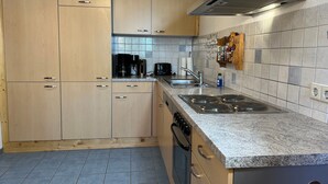 Une cuisine dotée de meubles en bois, d’un plan de travail en granit, d’un évier en acier inoxydable, d’une cuisinière et d’une hotte aspirante.