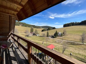 Eine Holzterrasse mit Blick auf eine ländliche Landschaft, einschließlich Häuser und Bäume.