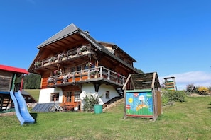 Eine Holzhütte mit Balkon, Rutsche und einem bunten Schild.