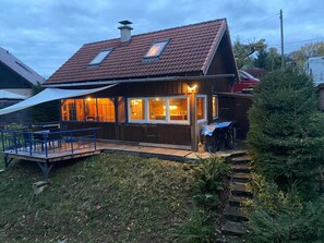 Une maison en bois avec un toit en pente, une terrasse et un espace extérieur couvert.