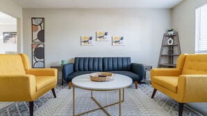 Un salon comprenant un canapé, deux fauteuils, une table basse et des œuvres d’art murales.