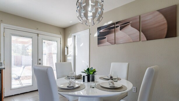 Un espace repas avec une table ronde, des chaises blanches et un lustre moderne.