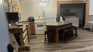 Una cocina acogedora con una isla de madera, un área de comedor con un sofá y un reloj en la pared.