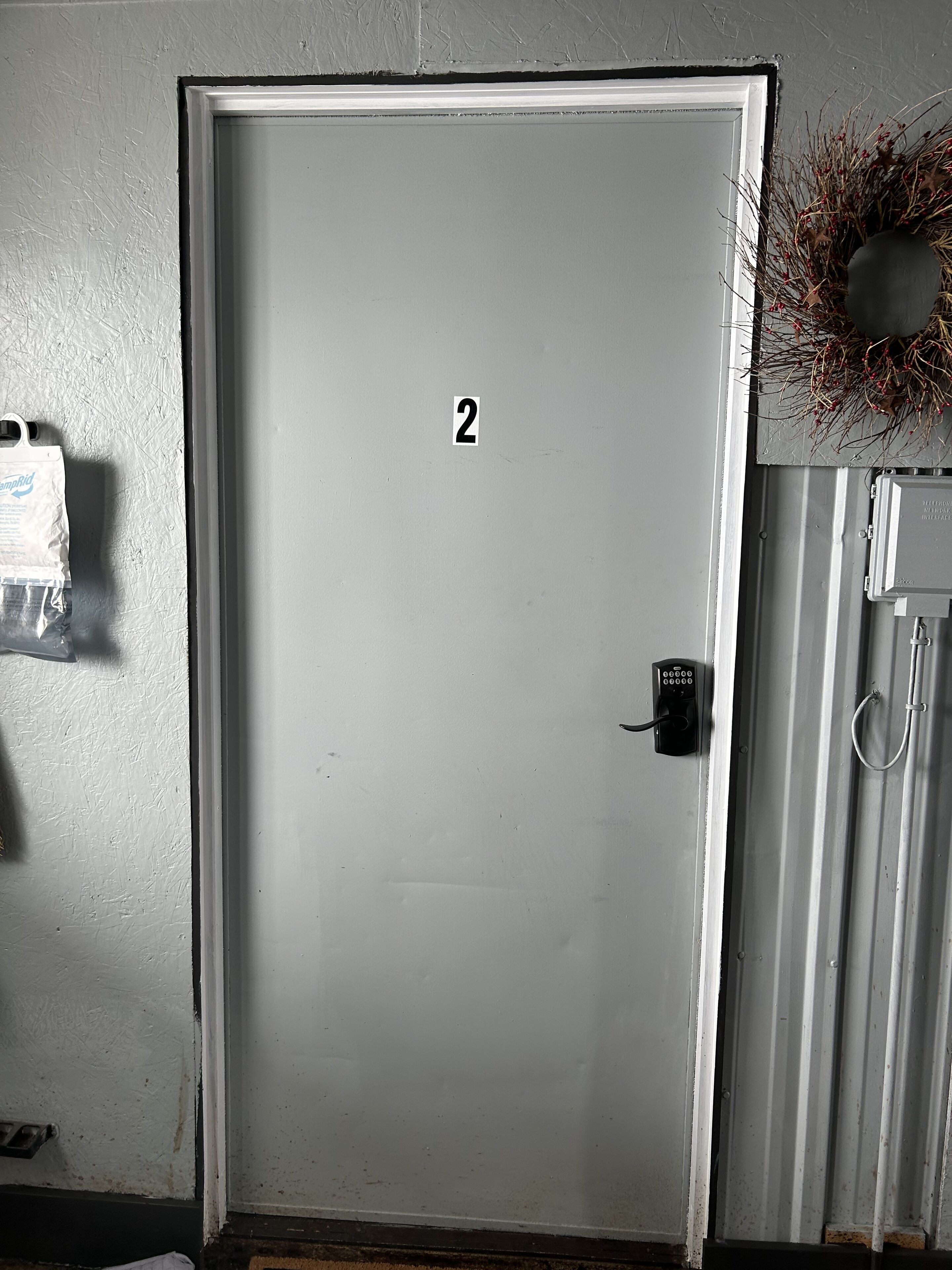 A door with a number 2 sign, a keyhole, and a wall-mounted electrical box.