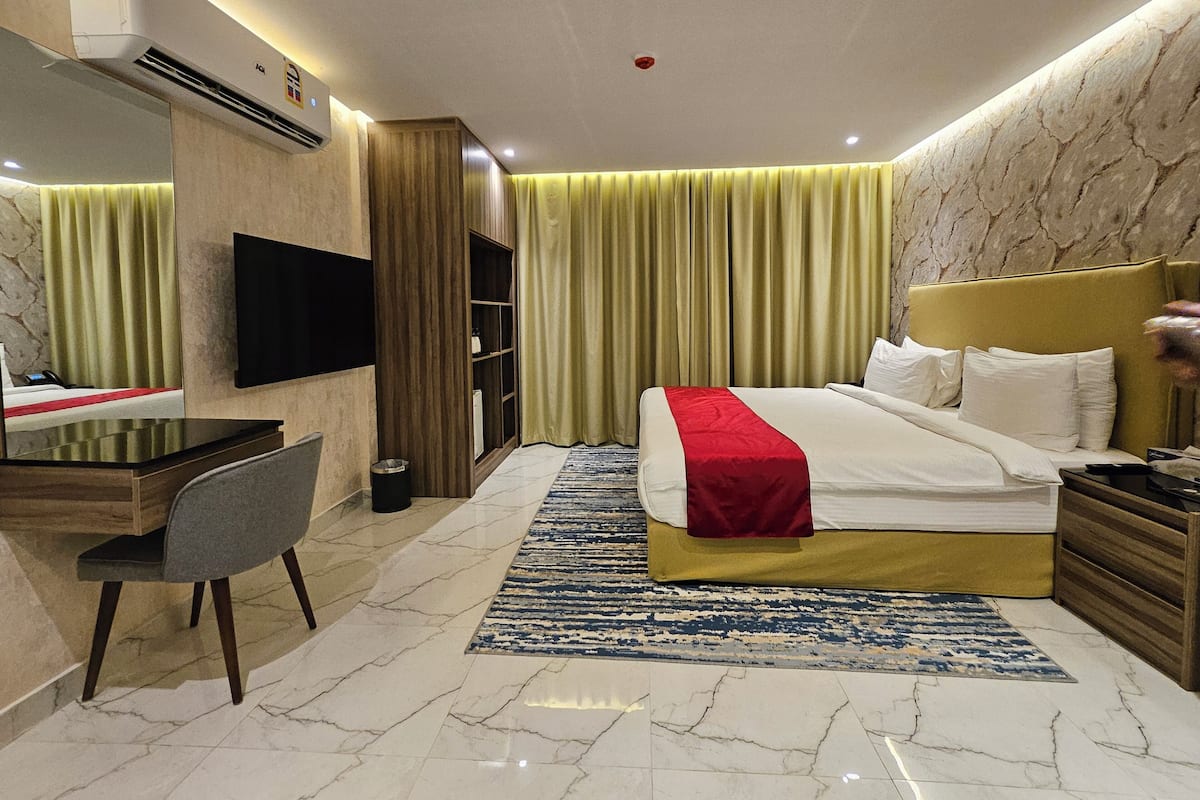 Una habitación de hotel moderna con cama, escritorio, silla, televisor y minibar.