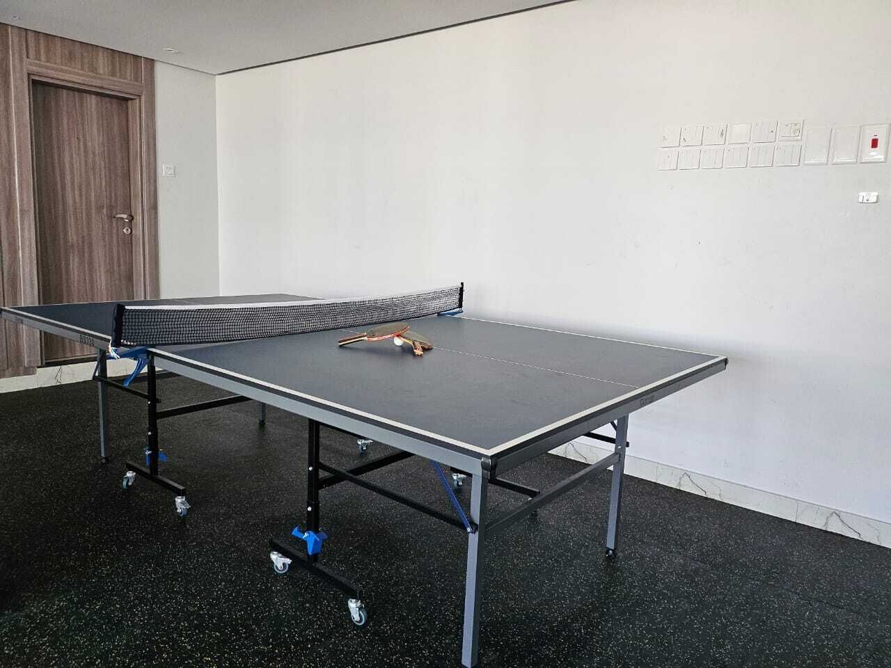 Ein Tischtennis-Tisch in einem Raum mit Holztür und weißen Wänden.