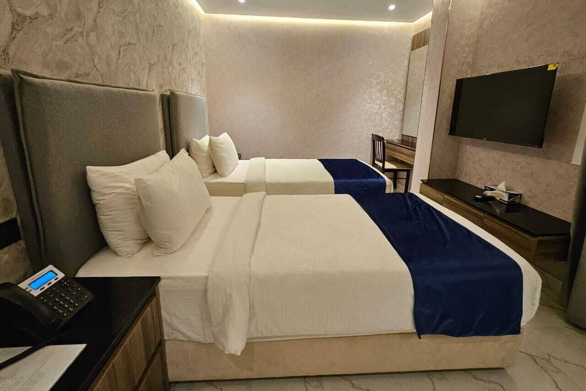 Una habitación de hotel moderna con dos camas, un escritorio, una silla, un televisor de pantalla plana y un teléfono.