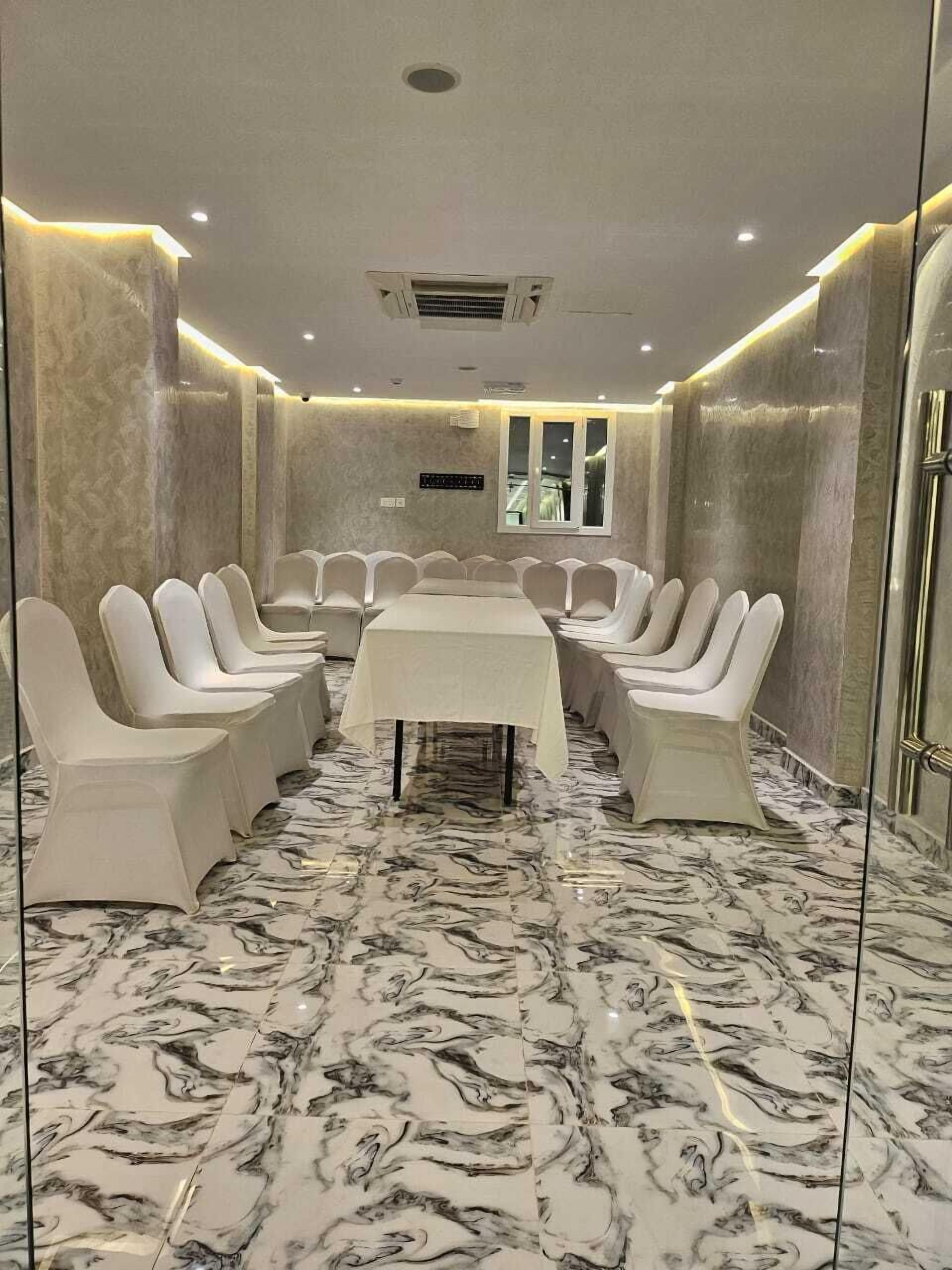 A conference room with a marble floor, white chairs, and a table.