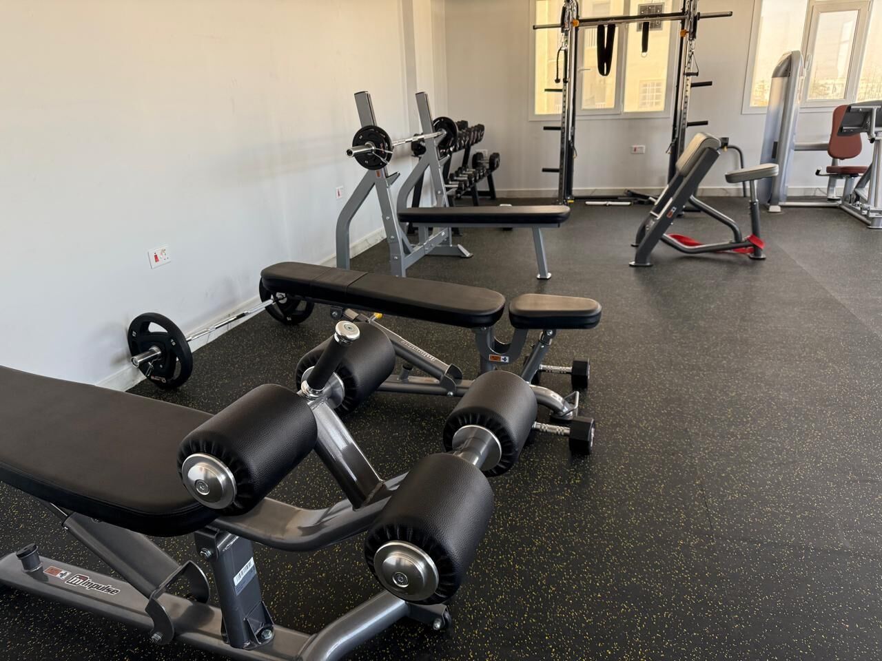 Un gimnasio con diferentes equipos de ejercicio, incluyendo bancos y mancuernas.