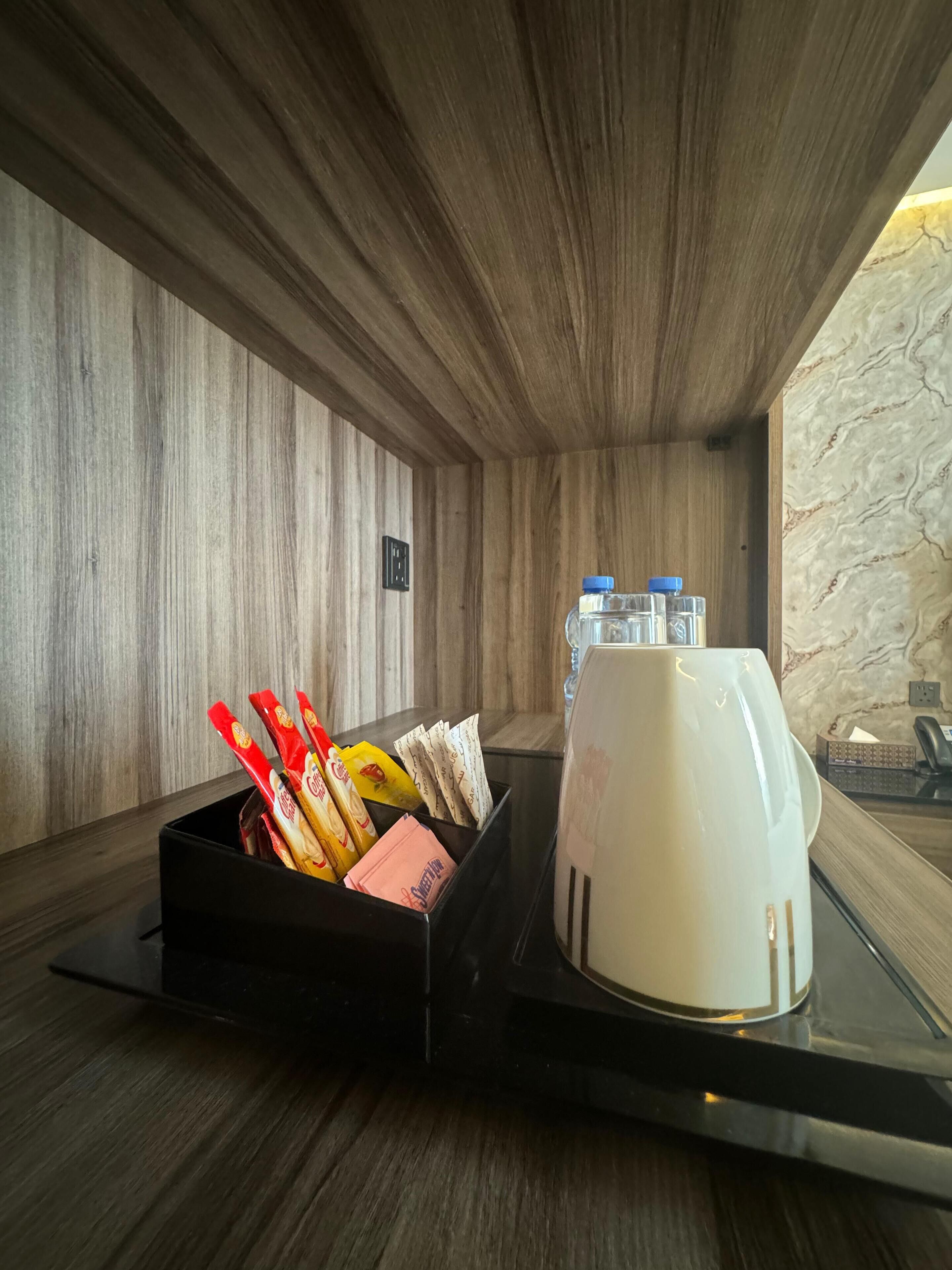 Habitación de hotel con interior de madera, una bandeja negra con aperitivos, una taza blanca y una pared de mármol.