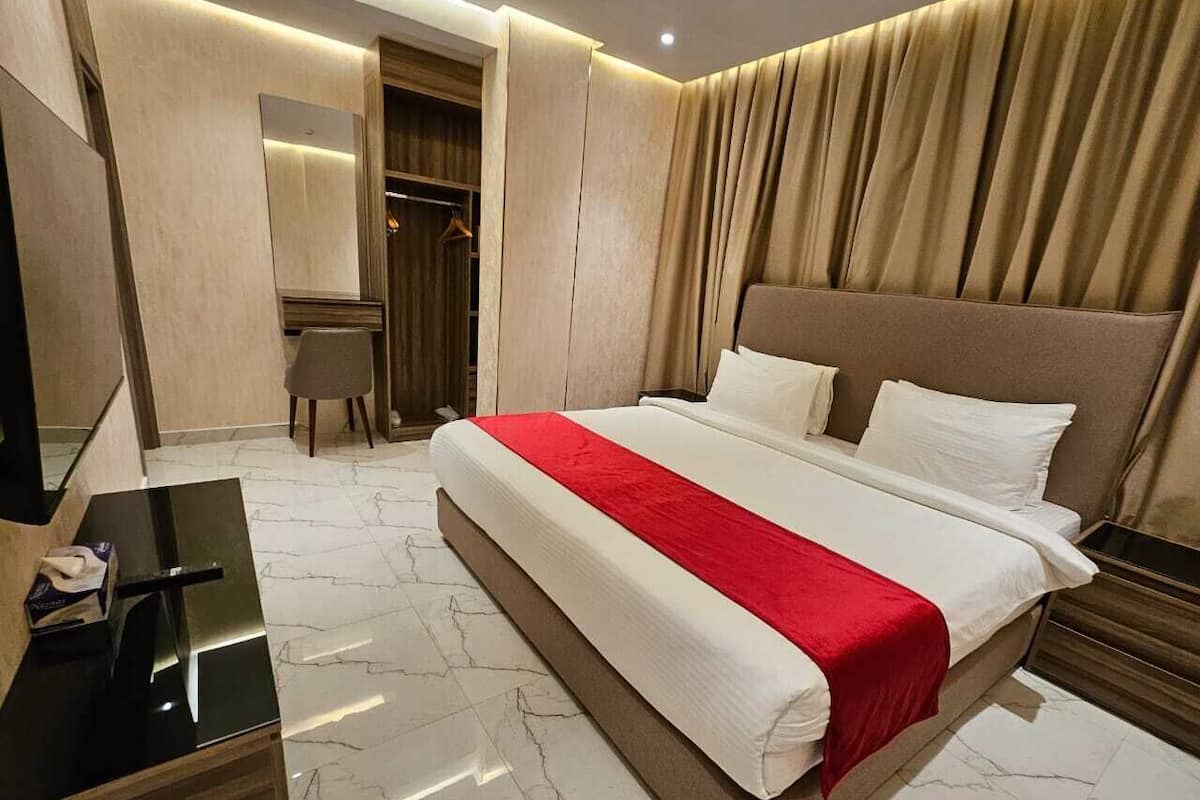Una habitación de hotel con una cama grande, un escritorio, una silla y un armario.