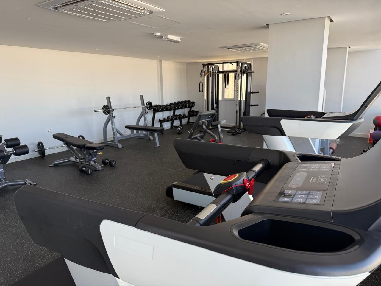 A gym with treadmills, weight machines, and dumbbells.