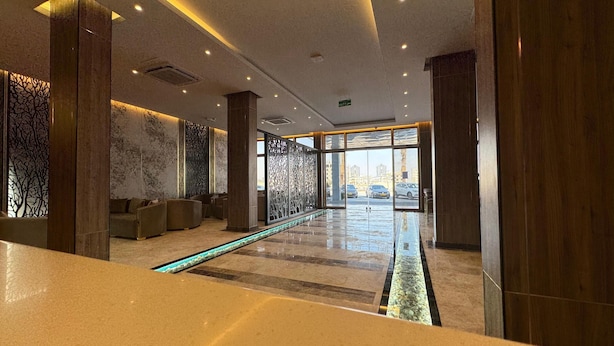 A modern lobby with a reception desk, seating area, and a glass barrier. - Royal Plaza Hotel - Duqm  (Duqm)