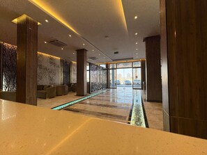 Un vestíbulo moderno con mostrador de recepción, zona de estar y una barrera de cristal.