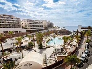 Un hôtel doté d’une piscine, de palmiers et offrant une vue sur l’océan.