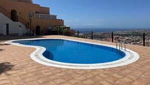 A swimming pool with a curved edge, surrounded by a tiled deck. - Salt and Sea Apartment, Sea View, Free Wi Fi (Costa Adeje)