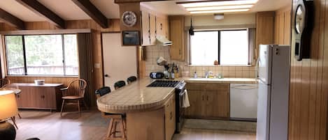 A kitchen with wooden cabinets, a central island, a sink, and a refrigerator.