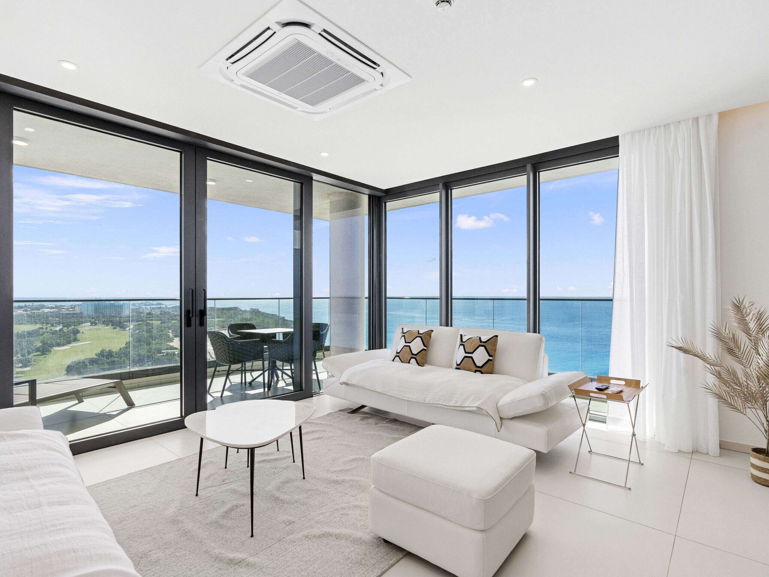 Un salon moderne avec balcon, des meubles blancs et une vue sur la mer.