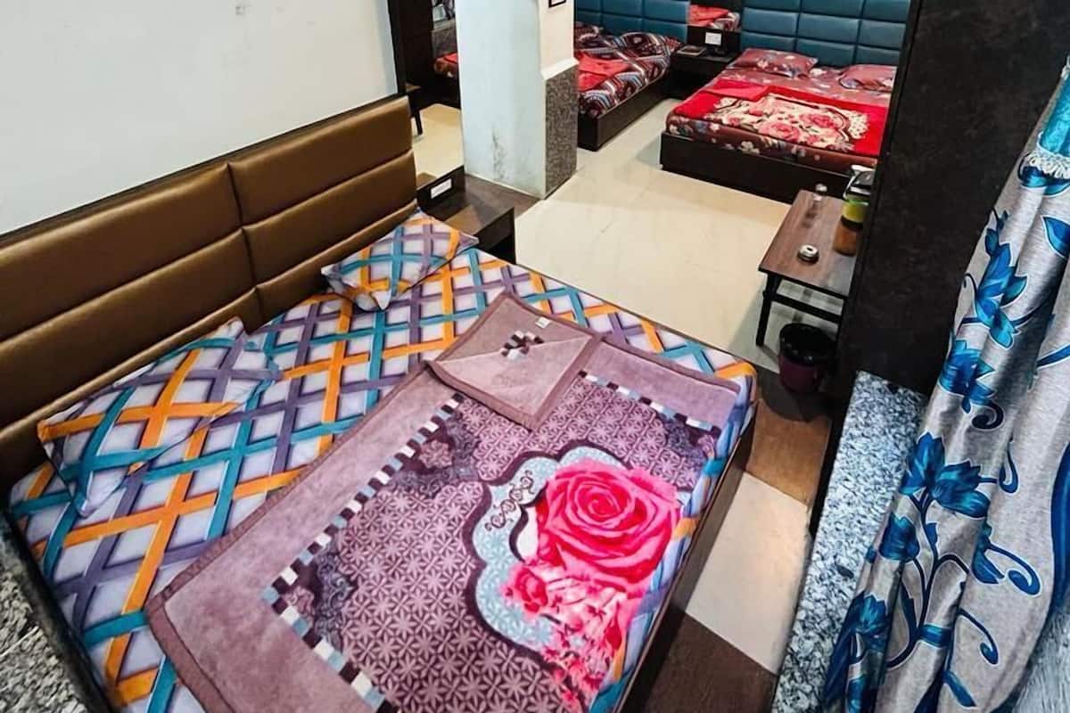 A hotel room with a brown headboard, a bed with patterned bedding, a blue sofa, and a television.