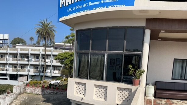 A hotel entrance with a large window and a sign indicating AC & Non AC rooms available. - Hotel Mansarovar (Abu Road)