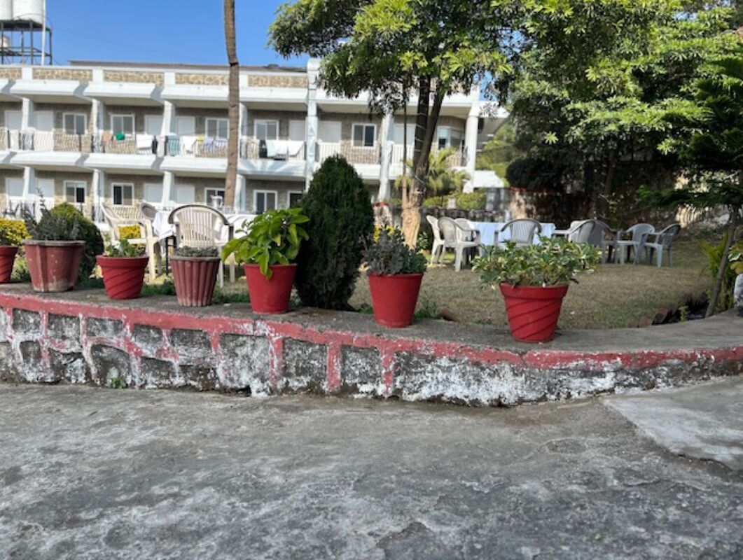 A hotel with multiple balconies, potted plants, and outdoor seating.