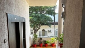 A narrow corridor with artificial green flooring, wooden doors, and potted plants. - Hotel Mansarovar (Abu Road)