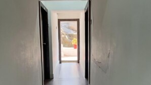 A narrow, well-lit hallway with a door at the end leading to an outdoor area. - Hotel Mansarovar (Abu Road)