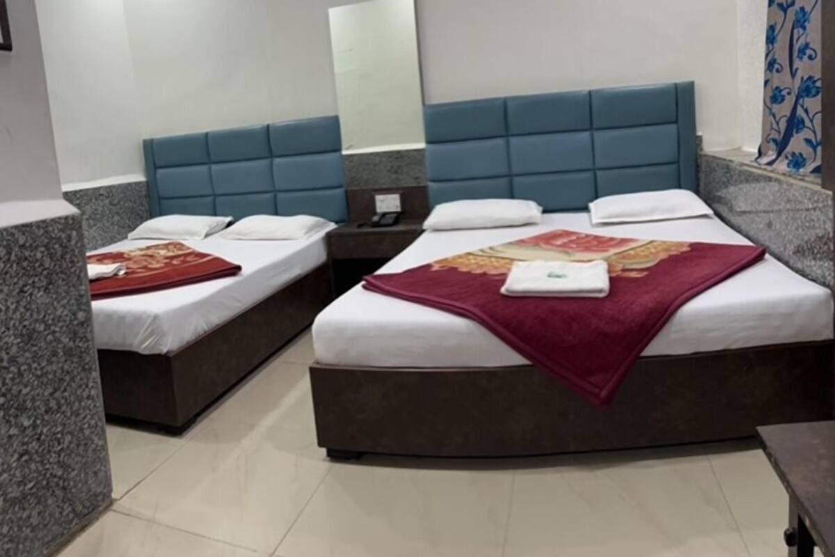 A hotel room with two beds, a large mirror, and a bathroom with a shower curtain.
