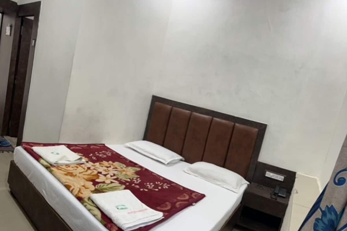 A neatly made bed with a floral bedspread, a white pillow, and a folded towel.