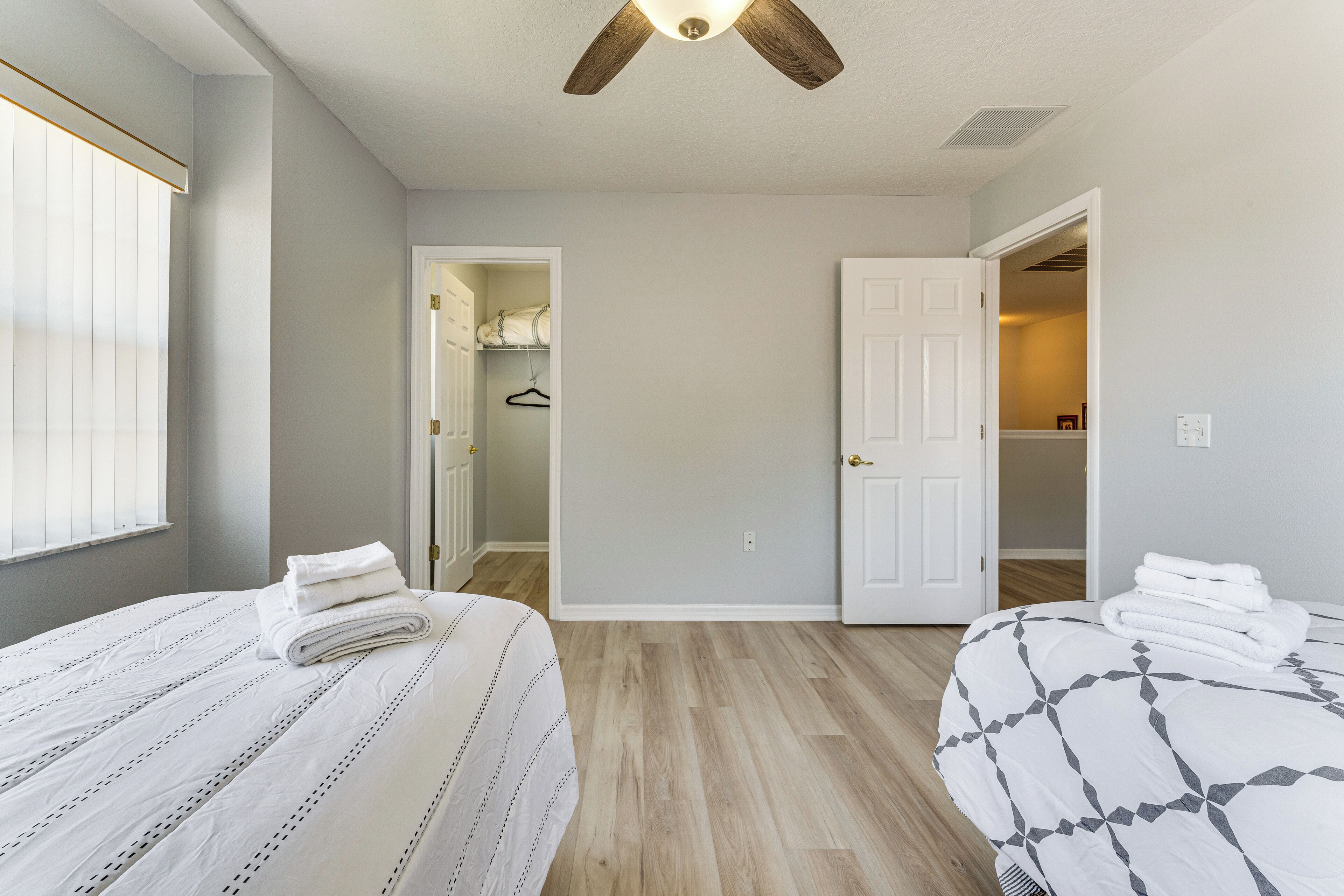 A bedroom with two beds, a closet, and a ceiling fan.