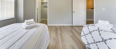 A bedroom with two beds, a closet, and a ceiling fan.
