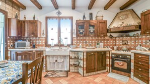 A kitchen with wooden cabinets, a microwave, a stove, and a dining area with a table and chairs. - Gorgeous home in Realmonte with WiFi (Realmonte)