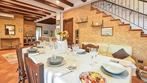 A dining area with a stone wall, wooden beams, and a staircase. - Gorgeous home in Realmonte with WiFi (Realmonte)