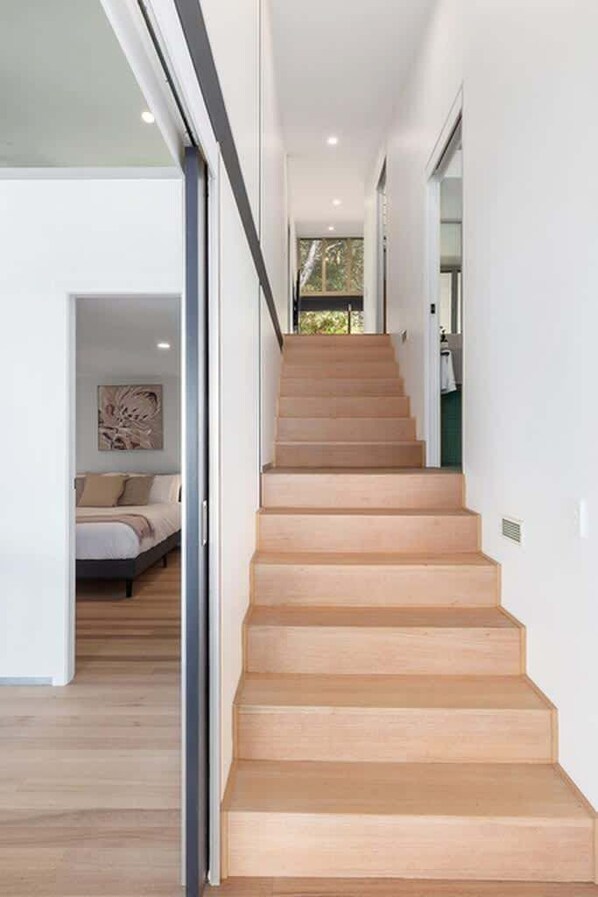 A staircase leading to a bedroom with a bed and a painting on the wall.