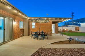 A patio area with a brick wall, a table with chairs, and an umbrella. - The Swing by Velo (Tucson)