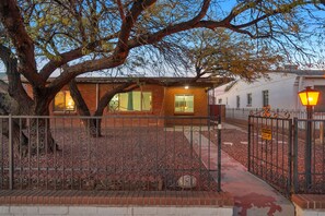 A building with a brick facade, a metal fence, and a tree in the foreground. - The Swing by Velo (Tucson)