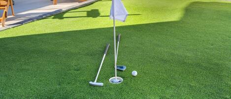 Instalación de minigolf con un putting green, una bandera y pelotas de golf.