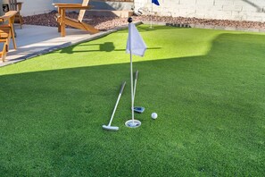 A miniature golf setup with a putting green, a flag, and golf balls. - The Swing by Velo (Tucson)