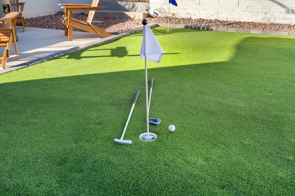 Un parcours de mini-golf comprenant un green d’entraînement, un drapeau et des balles de golf.